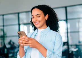 Mulher sorrindo enquanto utiliza o celular, representando a participação na pesquisa de satisfação da Hapvida pelo app.